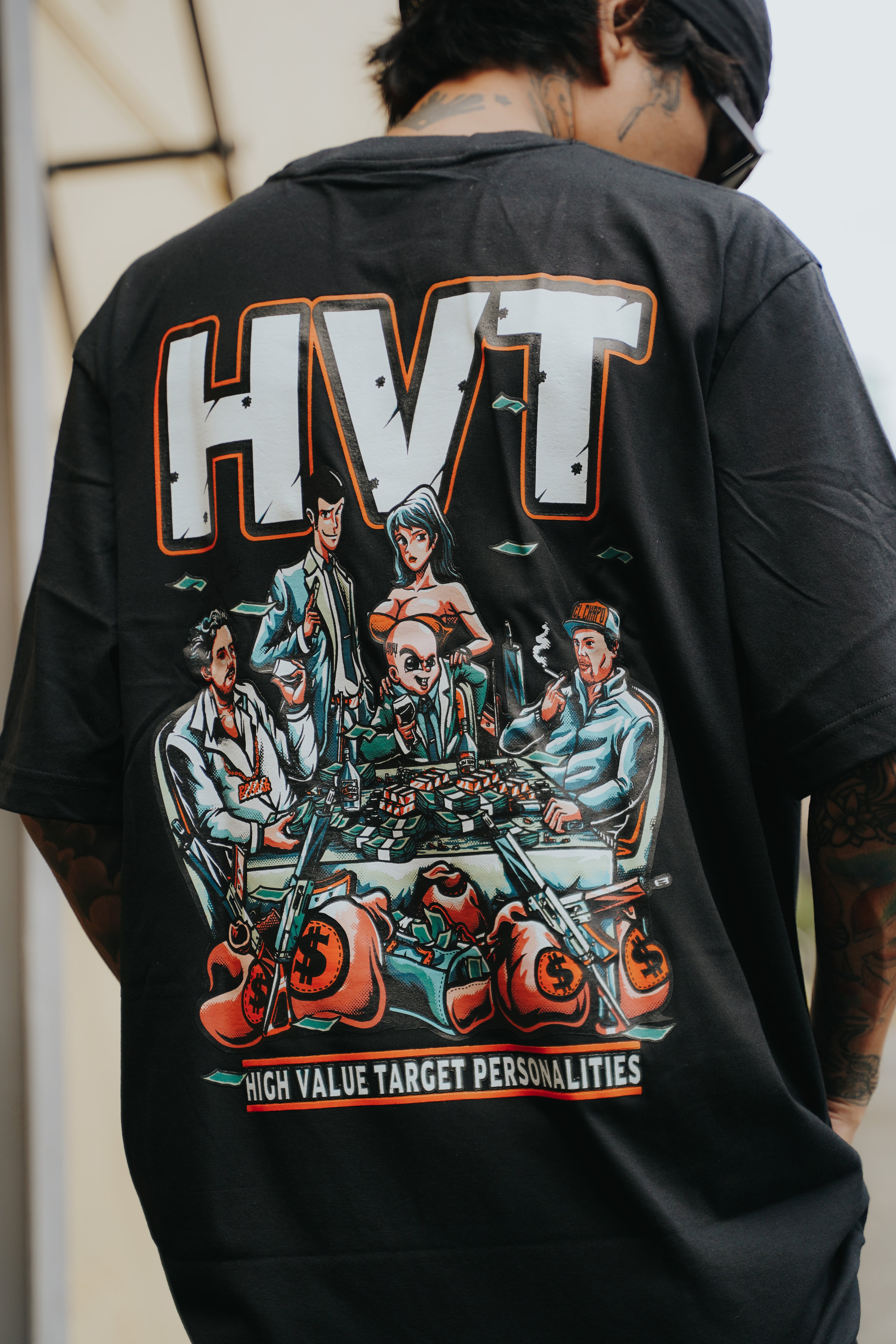 Black streetwear t-shirt featuring anime-style characters gathered at a table filled with cash, bold back graphic