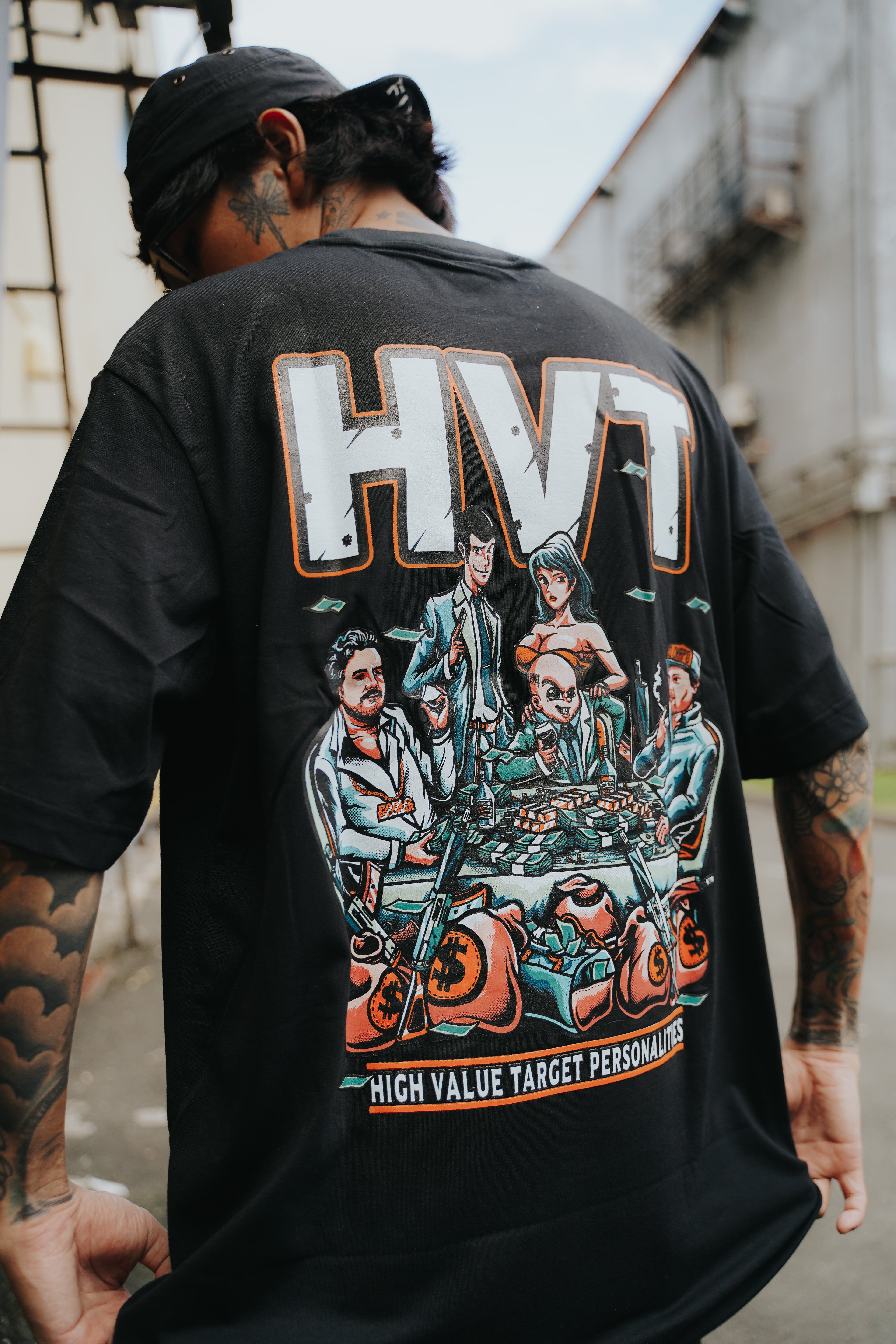 Oversized black tee with illustrated anime crew sitting around money stacks, detailed urban fashion back print