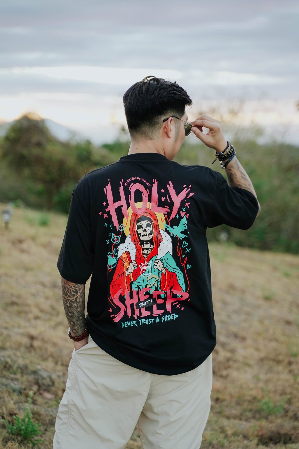 Black graphic tee showing skeleton holding sheep on shoulders, edgy artwork with never trust the sheep slogan